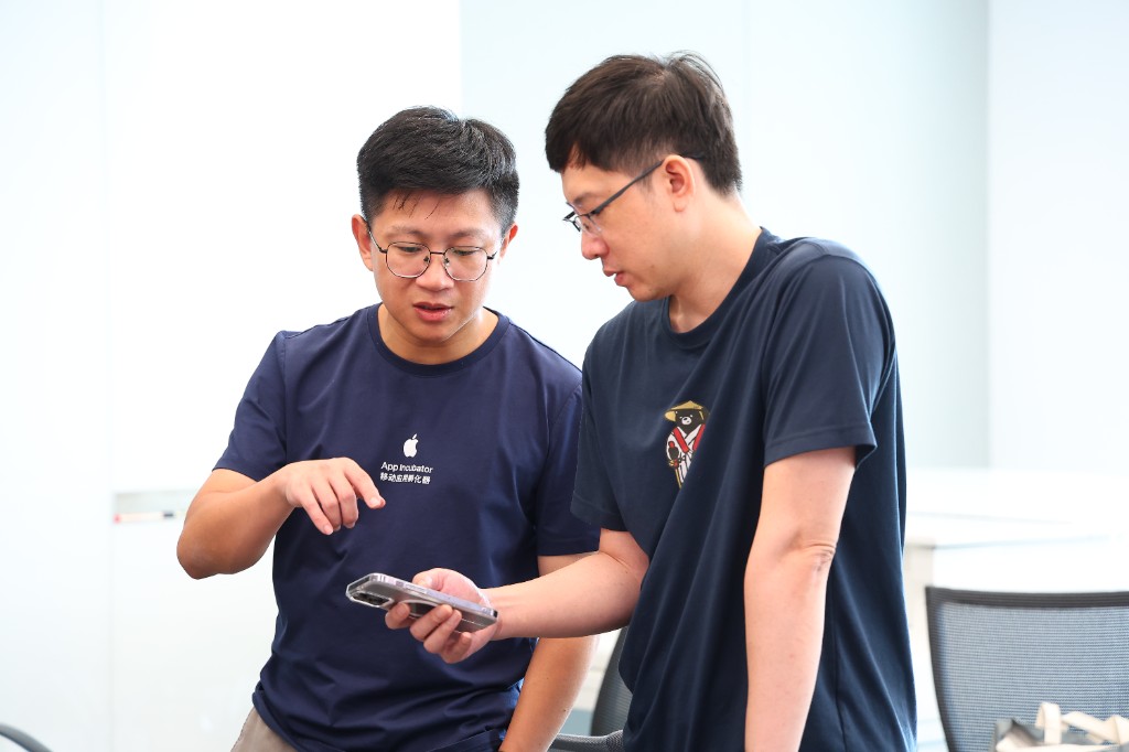 孵化器里两位成员一起看手机上的产品